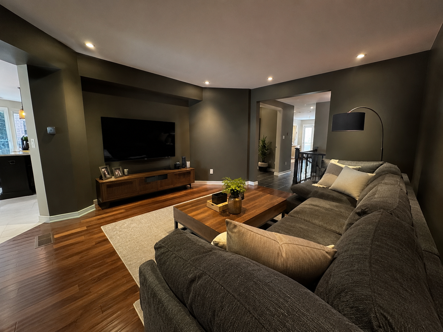 Moody dark green living room with sectional and mounted TV